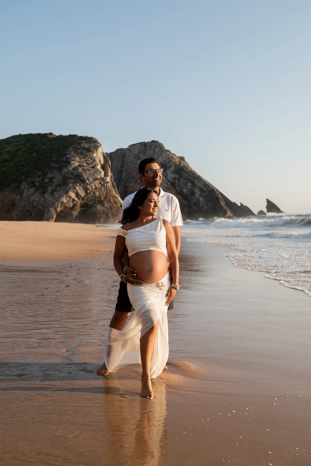 Casal grávido a caminhar na praia